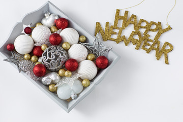 Christmas decorations in a wooden gray tray: balls, hearts, stars and in golden letters written Happy New Year