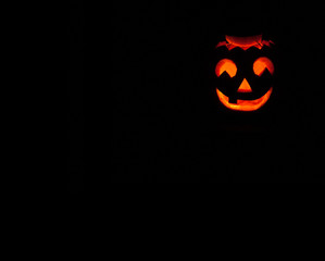 Illuminated halloween pumpkin on black background. Smile with one tooth. Halloween tradition.
