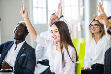 Confident business people raising hands to answer questions of lecturer of course business trainer