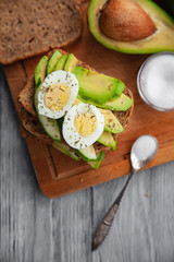 one avocado and sandwiches with egg and spices on a wooden Board