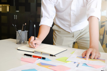 Business doing analysis data and writing on notepad paper.