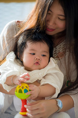 Fototapeta na wymiar lifestyle close up portrait of young happy and beautiful Asian Chinese woman holding her sweet adorable baby girl sitting and enjoying together in mother daughter love