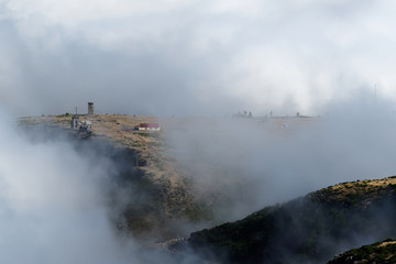 Looking through the clouds at an abandoned building on the mountain peak