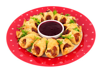 Savoury pigs in blankets with cranberry sauce dip isolated on a white background