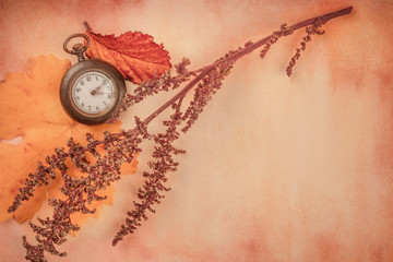 A vintage watch with autumn leaves, shot from above on a sheet of old paper with copy space, toned image