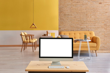 Decorative yellow and brick wall living room concept, close up desktop screen on the wooden desk.