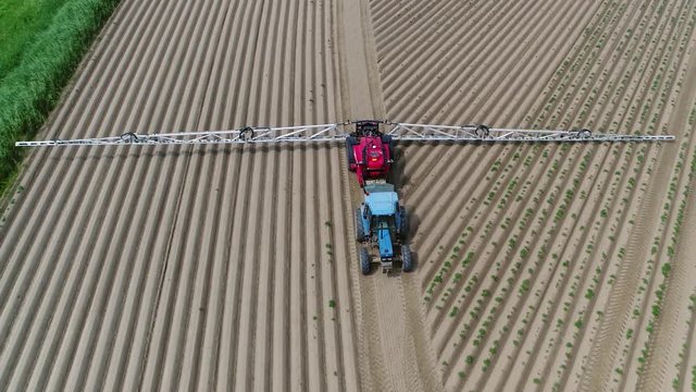Aerial footage of tractor pulling a sprayer is device used to spray liquid commonly used for projection of water weed killers crop performance materials and pest maintenance chemicals 4k quality