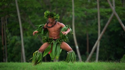 Barefoot Tahitian Polynesian man in hula skirts and flower headdress performing a traditional warrior dance at celebration ceremony French Polynesia South, Pacific,