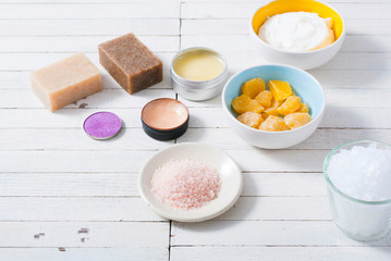 bath salts, beeswax , makeup base, powder compact, soaps and cosmetic creams on white wooden background