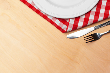 Empty plate and towel over wooden table background.