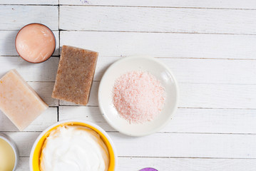 bath salts, beeswax , makeup base, powder compact, soaps and cosmetic creams on white wooden background