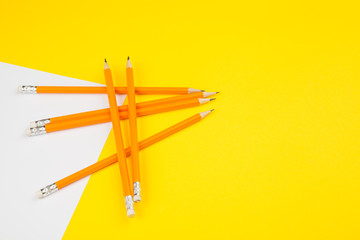 Orange pencils with blank paper  on bright yellow background