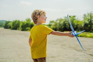 Happy kid playing with toy airplane against old runway background. Traveling with kids concept