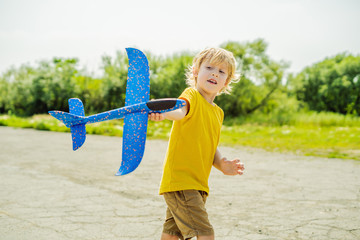 Happy kid playing with toy airplane against old runway background. Traveling with kids concept