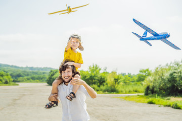 Happy father and son playing with toy airplane against old runway background. Traveling with kids concept