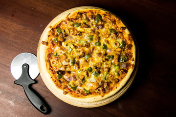 Pan Pizza take from top view with dark brown wood and cutter