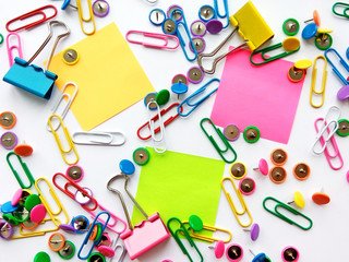 Colorful stationary, back to school, office, business and education concept. School and office supplies paper clips, pins, notes, stickers on white background, flatlay. Mock up. Top view, close up