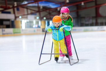 Child skating on indoor ice rink. Kids skate.