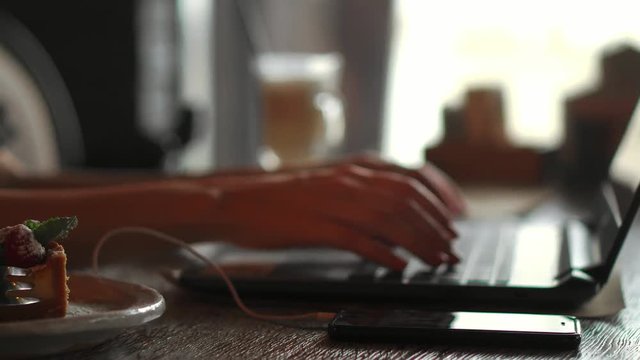 A female programmer typing source codes in a coffee shop with a relaxing working environment. Studying, Working, Technology, Freelance Work, Web Design Business, and Web Development Concept.
