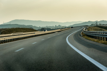 Fototapeta premium Winding Highway through Rural Landscape with few cars on a cloudy Overcast Day
