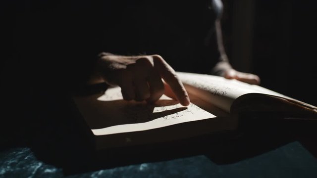 Someone is leafing through old book in dark