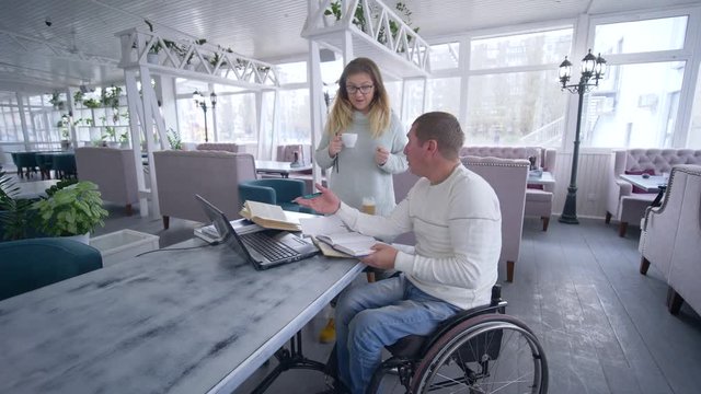 freelance lifestyle of invalid, Creative disabled man on wheelchair with female with cup coffee working on laptop computer for planning and managing business and develop ideas