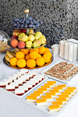 Cakes lined up in rows on dessert buffet with fruit