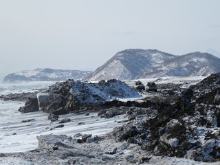 Plakat Pacific Ocean, waves and views of the snow-covered hill in winter in sunny weather in Kamchatka, Russia