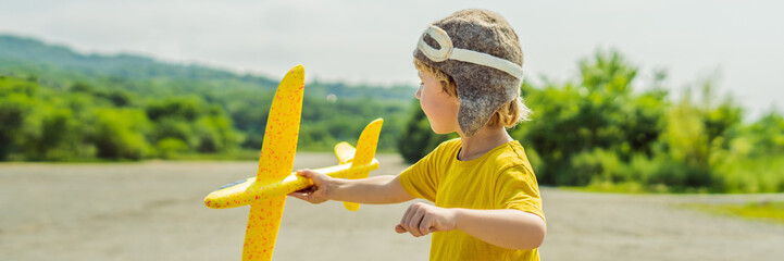 Happy kid playing with toy airplane against old runway background. Traveling with kids concept BANNER, LONG FORMAT