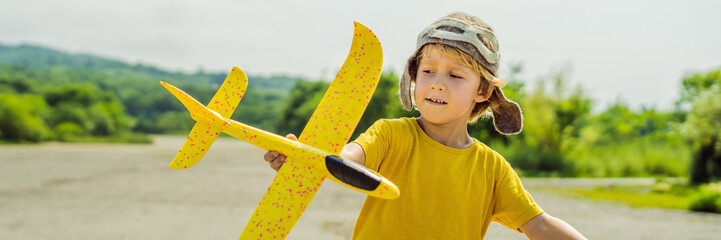 Happy kid playing with toy airplane against old runway background. Traveling with kids concept BANNER, LONG FORMAT