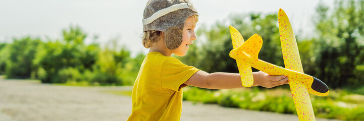 Happy kid playing with toy airplane against old runway background. Traveling with kids concept BANNER, LONG FORMAT