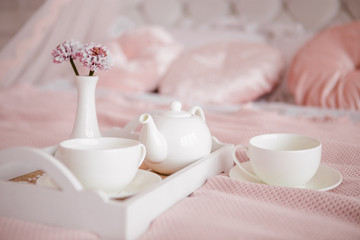 Breakfast in bed with flowers and white cups.