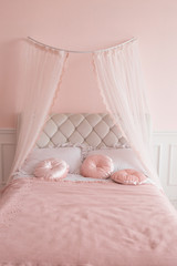 Four-poster bed with pink pillows.