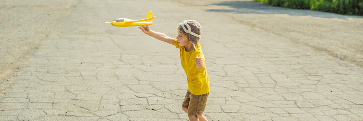 Happy kid playing with toy airplane against old runway background. Traveling with kids concept BANNER, LONG FORMAT