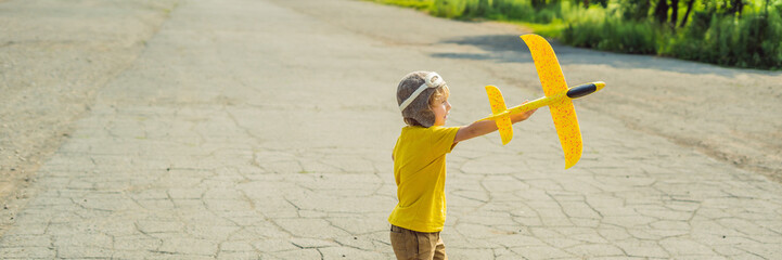 Happy kid playing with toy airplane against old runway background. Traveling with kids concept BANNER, LONG FORMAT