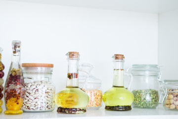 Cereals, beans, olive oil in glass jars.
