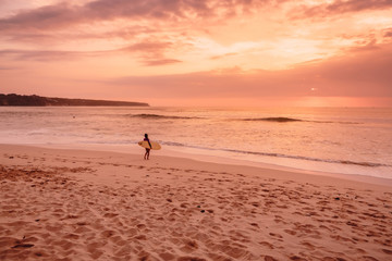Fototapeta na wymiar Surf woman with surfboard go to ocean for surfing. Surfer woman on beach at bright sunset