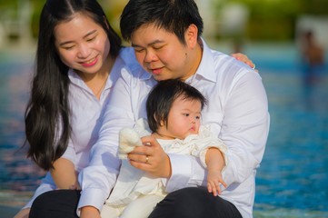 cheerful and sweet wife and husband couple with mother holding baby girl and man playing with little daughter in Asian Korean family love and happy parents concept