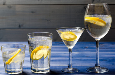 Hangover and detox. Detox after party. Health care concept. What to drink on christmas party. Cocktail glasses with water and slice of lemon on blue wooden surface. Detox drink to feel better