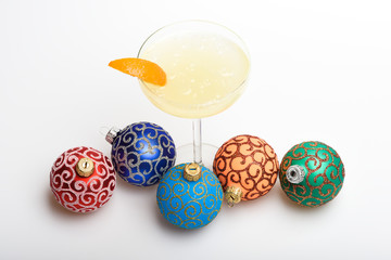 Bar winter season cocktail menu. Winter cocktail drink concept. Alcohol cocktail margarita with piece of orange near christmas balls ornaments on white background. Celebrate new year cocktail