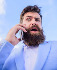 Man bearded surprised businessman hold mobile phone sky background. Hipster smartphone call...