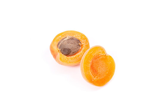 Several of harvested apricots whole and halved on white background..