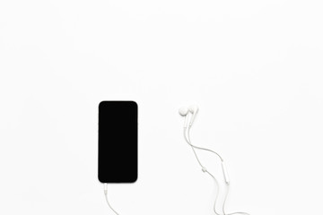 Mobile phone with white earphones isolated on white