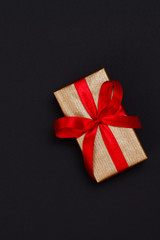Gift box with red ribbon on black background.