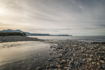 River joins the sea on a pebble beach in Corsica