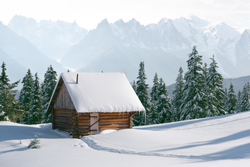 Fantastic winter landscape with wooden house in snowy mountains. Christmas holiday concept