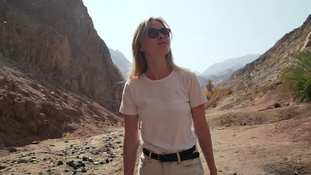 Blonde romantic woman circling around in desert at sunny hot day shaky footage