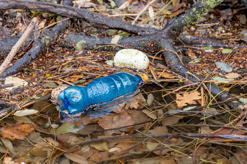 plastic beverage bottle floats on a watercourse with other garbage