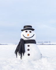 Funny snowman in stylish hat and black scalf on snowy field. Merry Christmass and happy New Year!