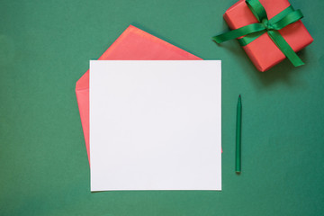 Christmas empty blank letter to Santa or invitation with giftbox on green. Top view.